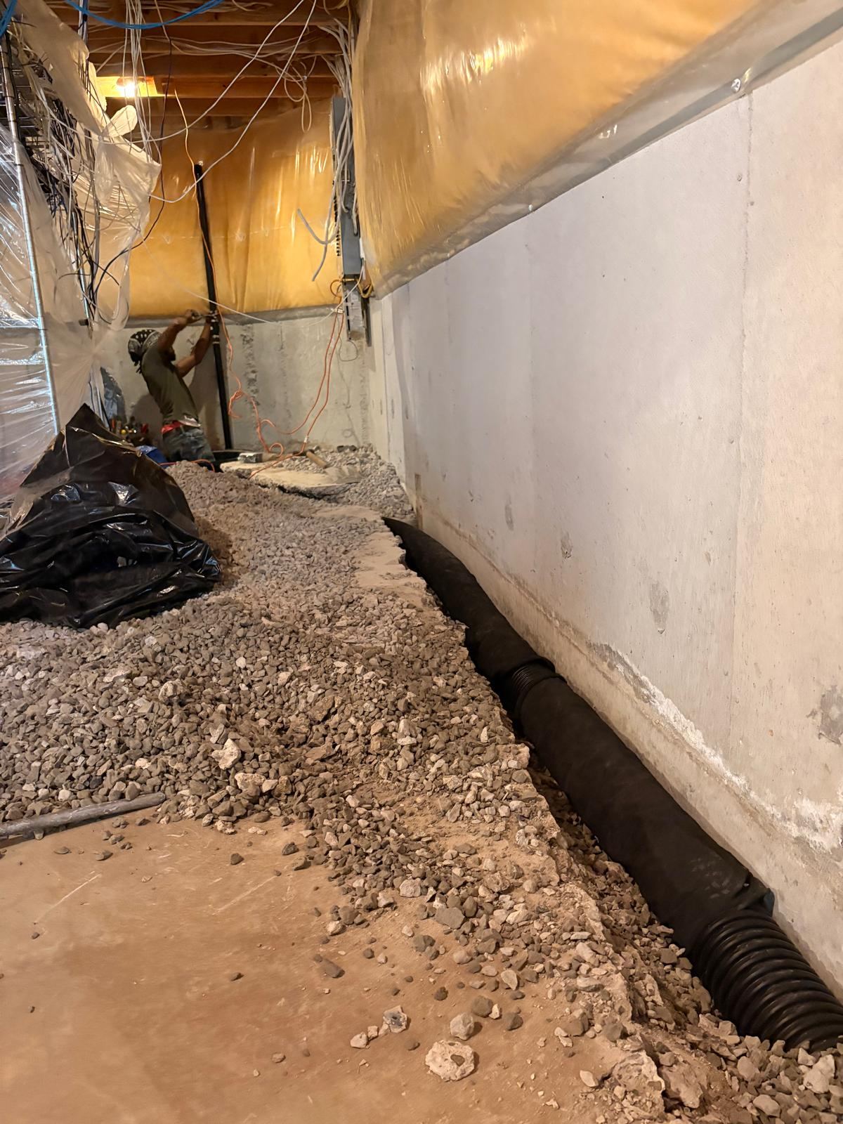 Sump pump installation in progress with drain tile along the foundation wall