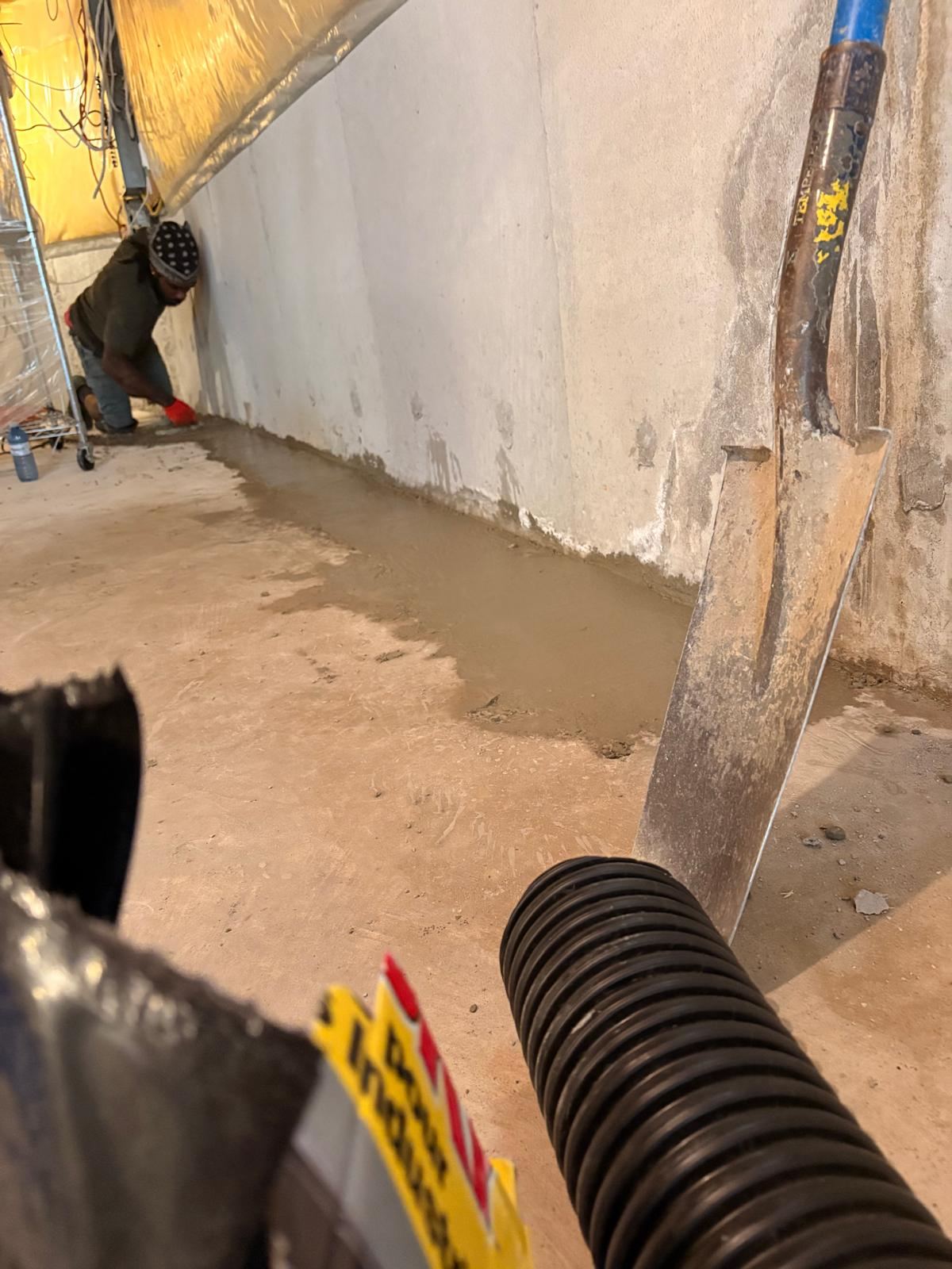 Cement being placed over weeping tile leading to a sump pit